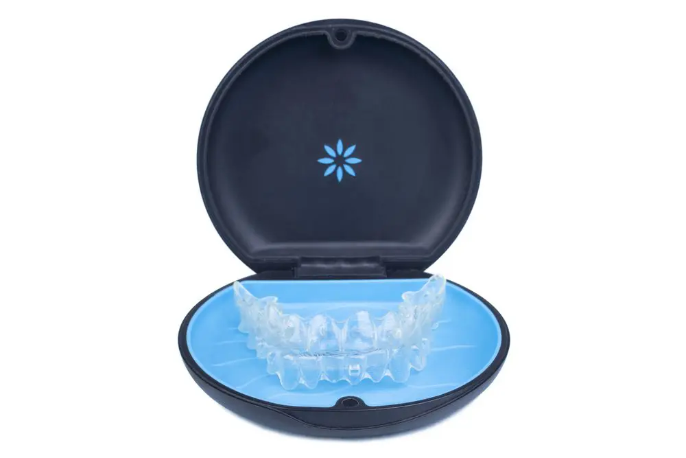 Isolated container with transparent invisalign aligner retainers or removable braces on white background