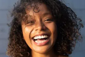 Close up young African American woman with curly hair laughing