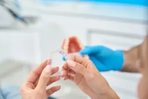Close-up female holding transparent aligner that are effective for moderate crowding of front teeth, it helps in straightening and shifting of teeth in a proper position