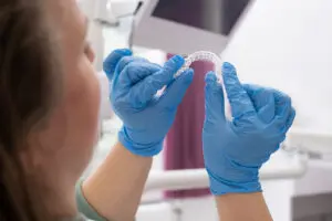 patient in dental clinic holding in hands and trying an invisible aligner for teeth correction and whitening,
