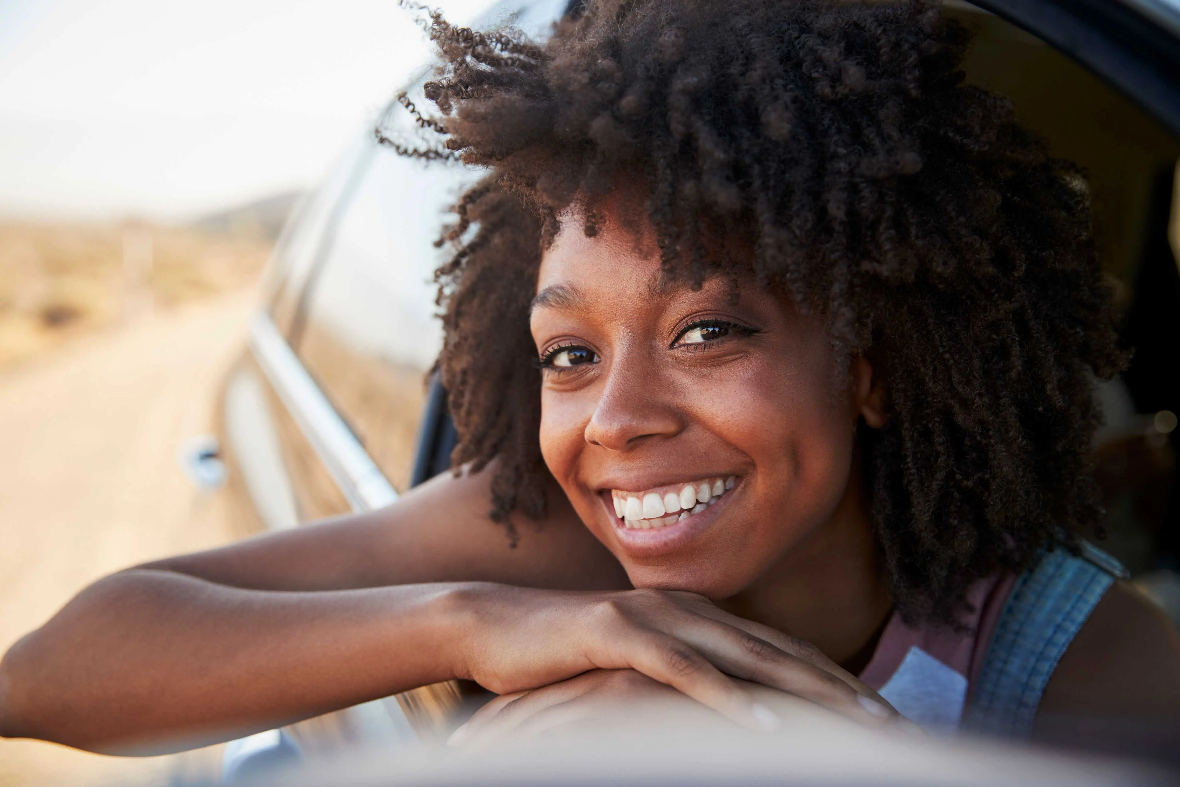 young woman smiling at the window of car