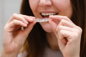 woman in front of mirror putting clear aligners