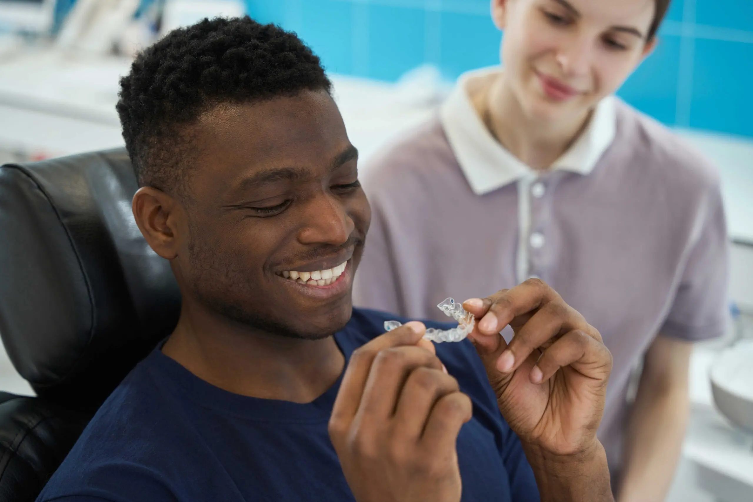 young men smiling holding clear aligners