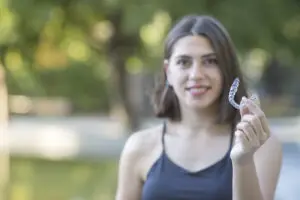 Beautiful smiling Turkish woman is holding an invisalign bracer