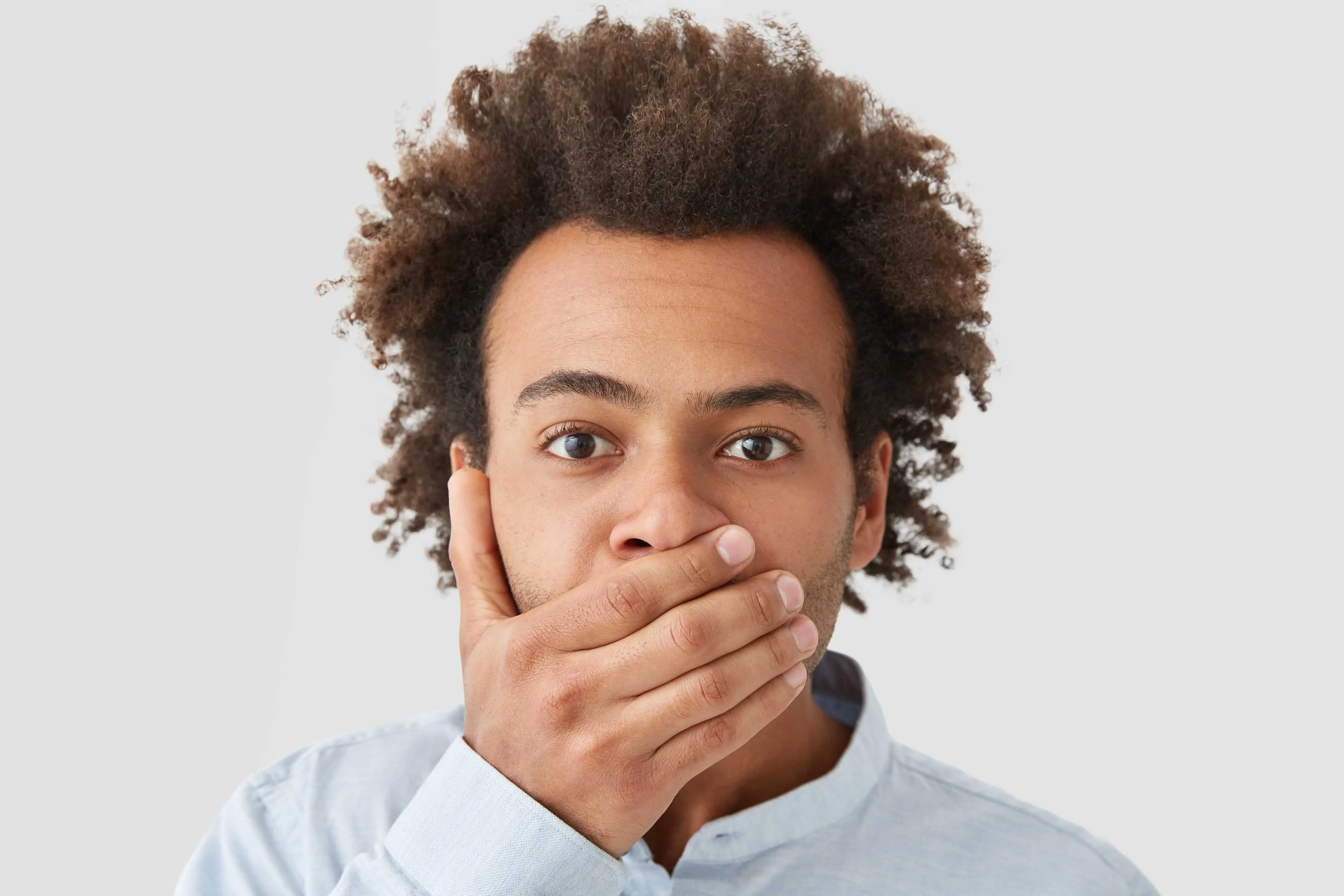 afro haired man covering mouth because of bad breath