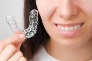 Close up woman holding a transparent removable braces for perfect smile. Orthodontic aligners for straightening and whitening teeth