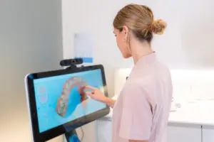 Dentist looking at 3D x-ray on client's monitor in modern dental clinic