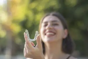Beautiful smiling woman is holding a clear aligner