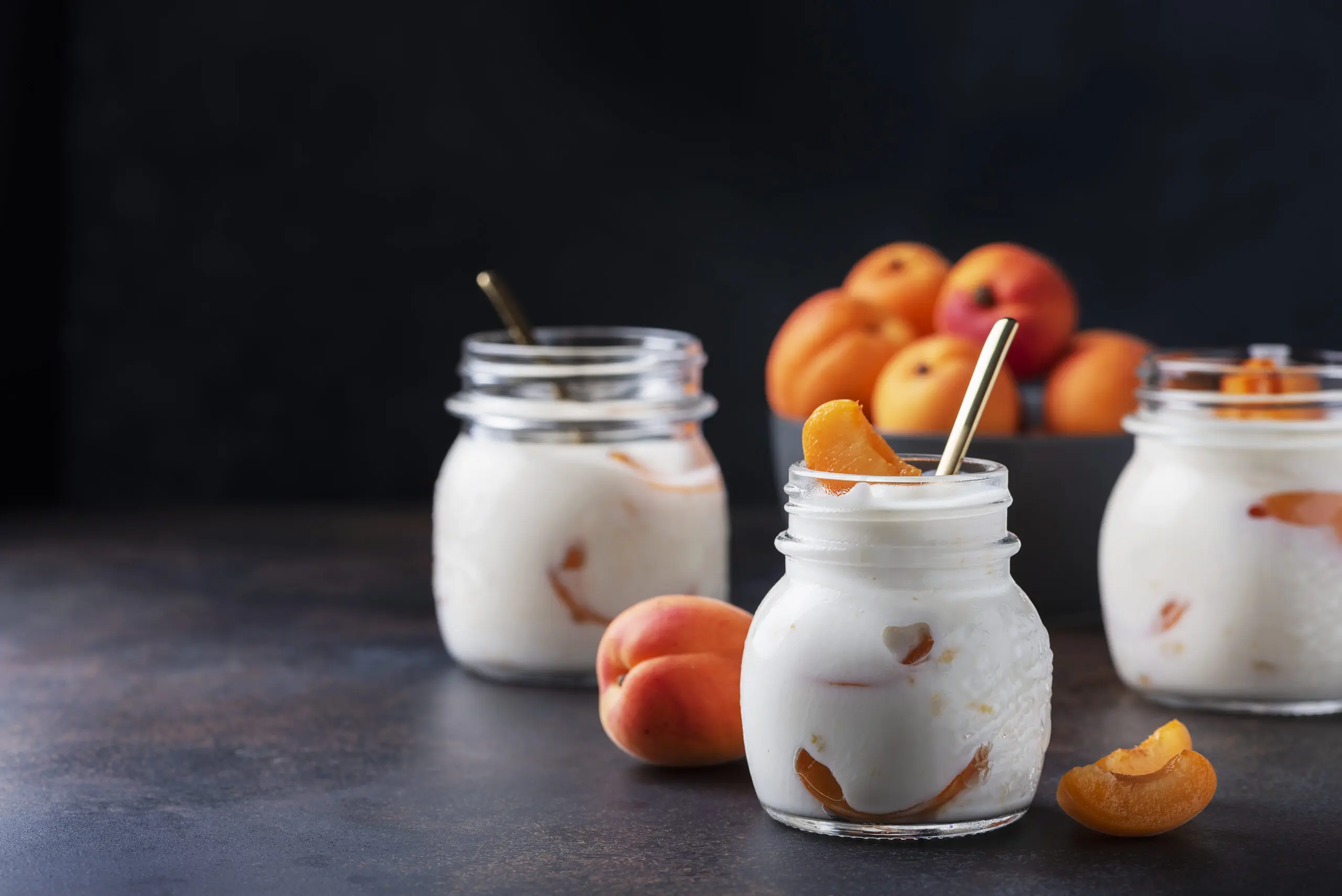 Sweet healthy yogurt with apricots on the dark table, selective focus image