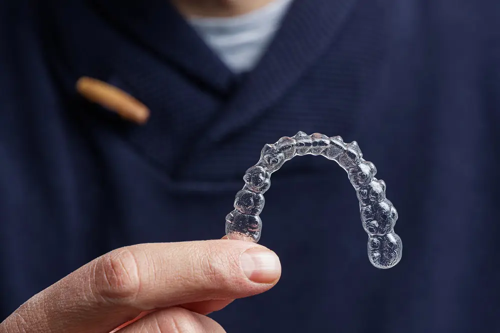 Man holding one transparent aligner.