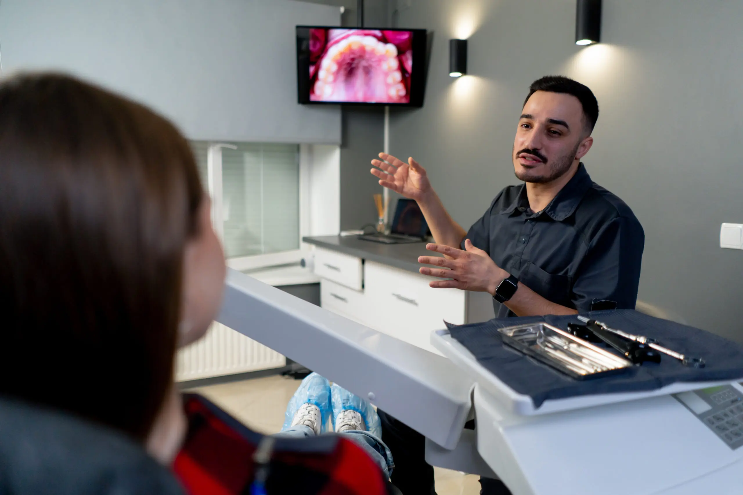 in a dental office a man shows a photo of teeth on a monitor for a young beautiful girl consultation