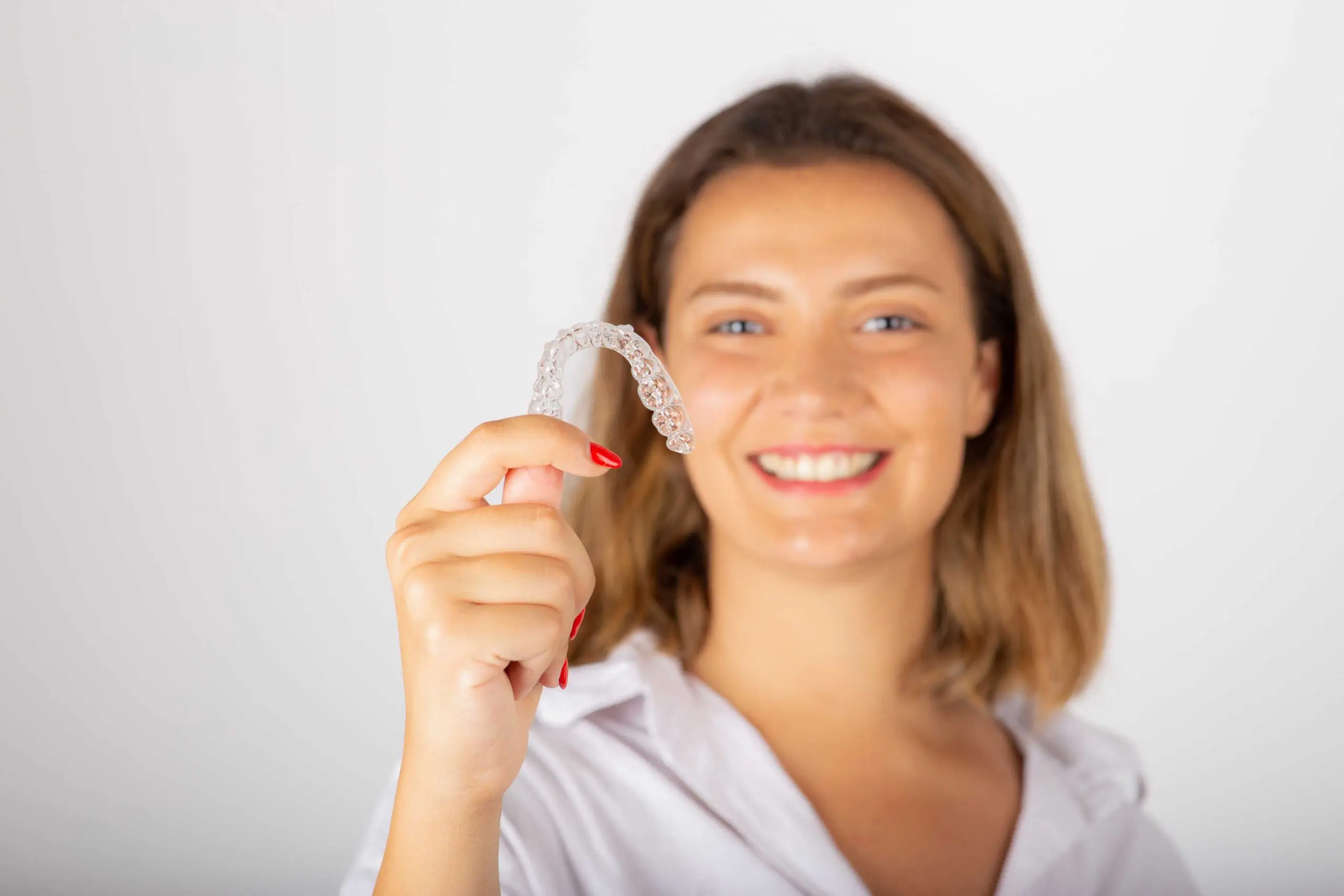 woman on white shirt holding up her retainers