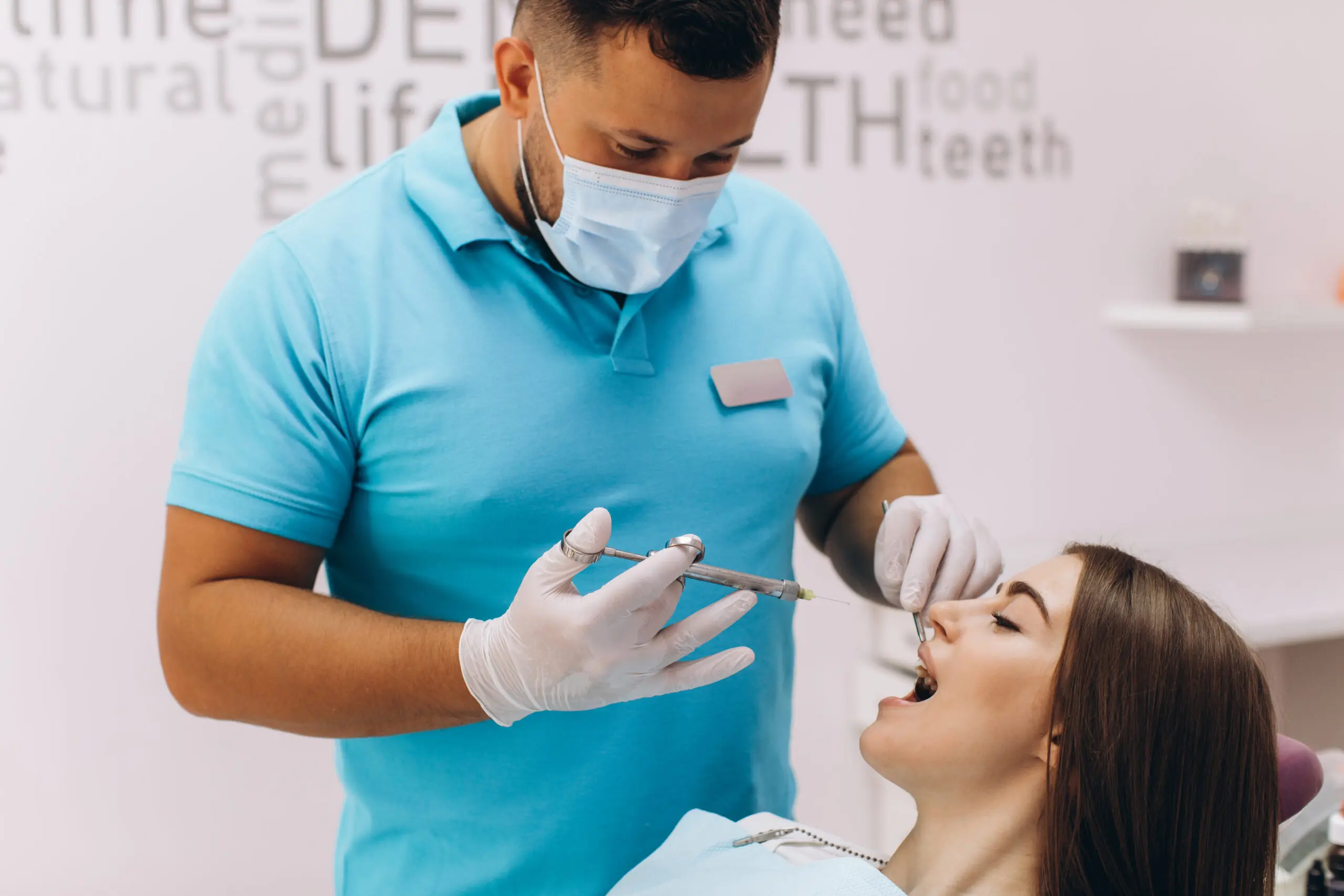 The dentist injects anesthesia to the girl patient, she is scared.