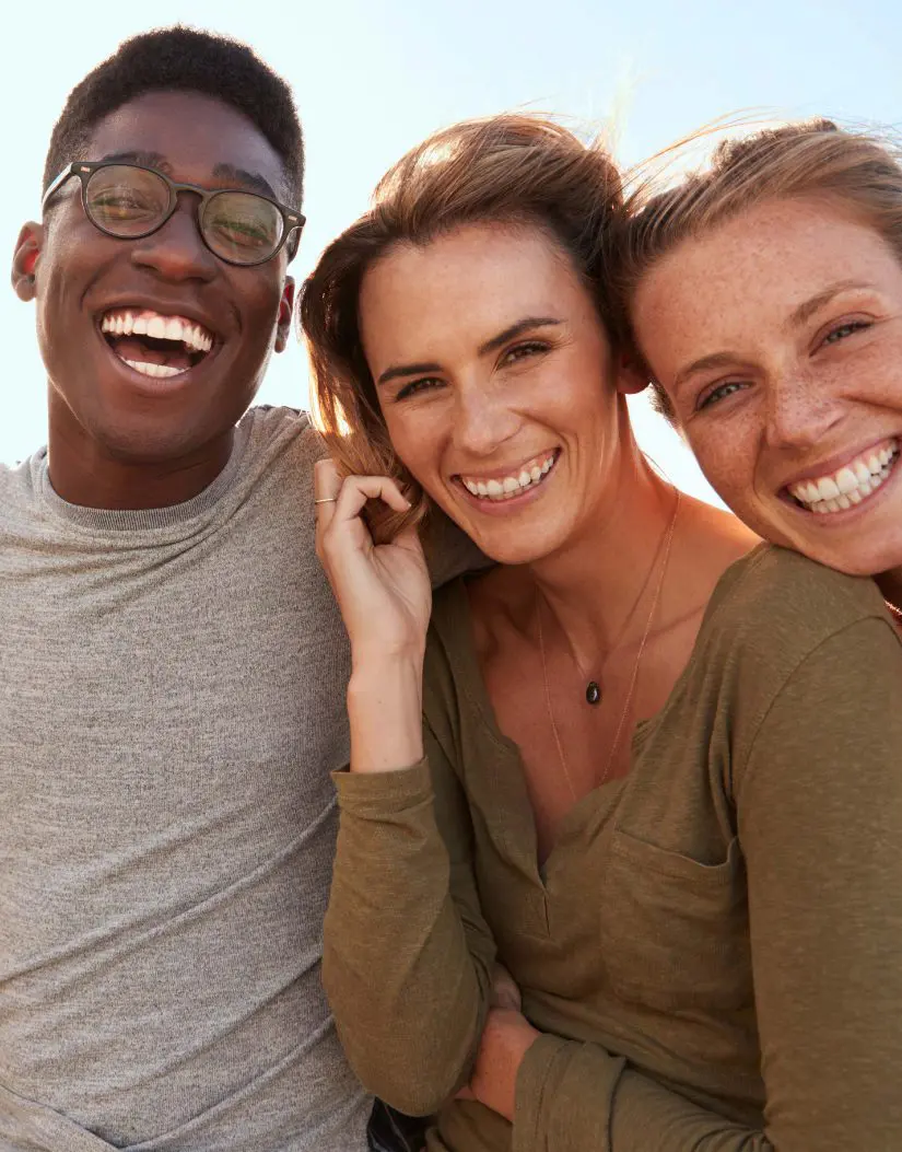 Group of three adults smiling outdoors