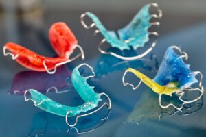 Colorful dental braces or retainers for teeth on glass background - Smilebliss Orthodontics