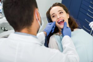 Selective focus of cheerful woman in braces opening mouth during