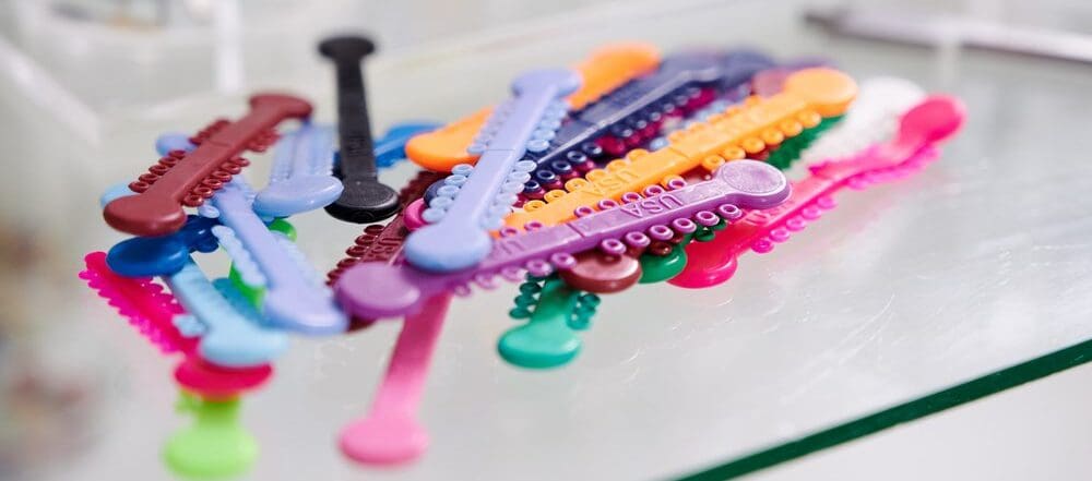 Glass table with multicolored orthodontic ligatures for braces.
