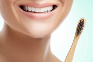 Female mouth with white teeth and bamboo toothbrush on white background