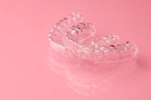 Two Invisible dental teeth aligners on the pink background. Orthodontic temporary removable braces