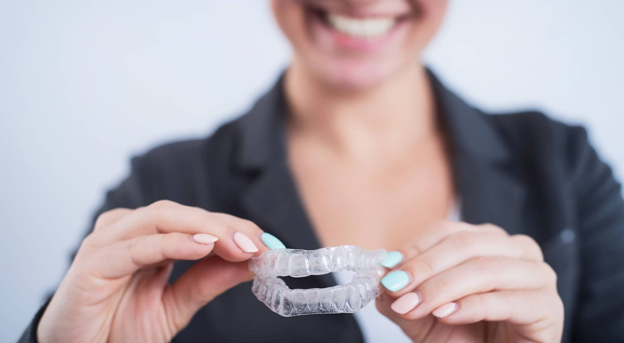 woman smiling holding clear aligners