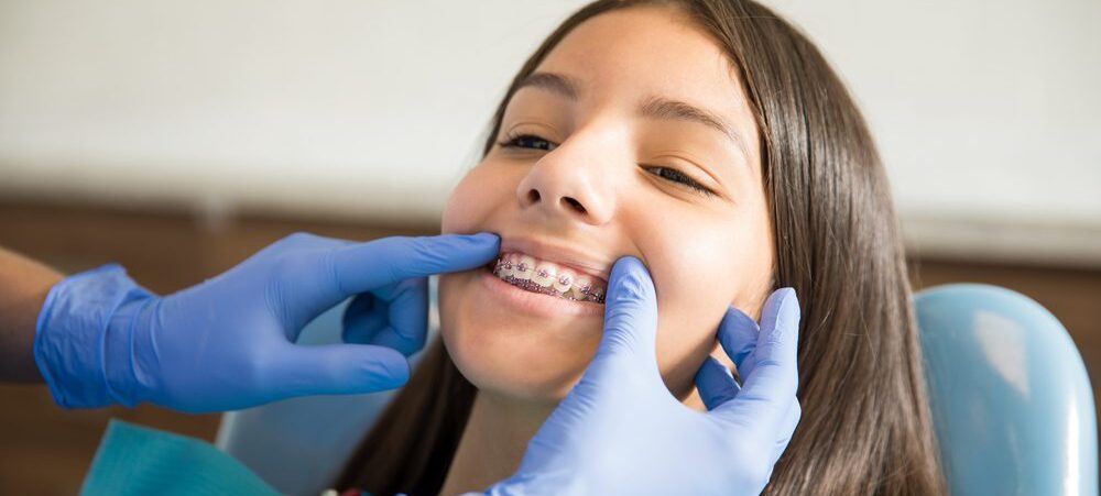 Girl With Braces Being Examined By Dentist In Clinic