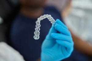 Unrecognizable young orthodontist holding trainer dental braces.