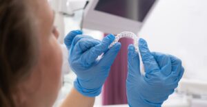 patient in dental clinic holding in hands and trying an invisible aligner for teeth correction and whitening,