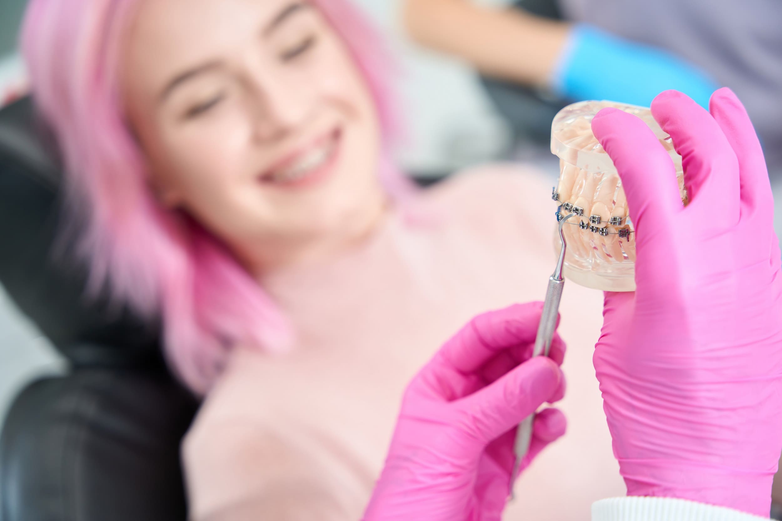 Doctor demonstrates model of dentition with braces to joyful patient