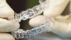 Close-up shot of doctors hands in gloves holding silicone mouth guard. Teeth care