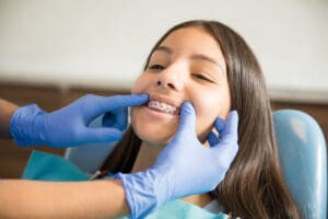 Teenage girl with braces being examined by dentist wearing gloves at clinic