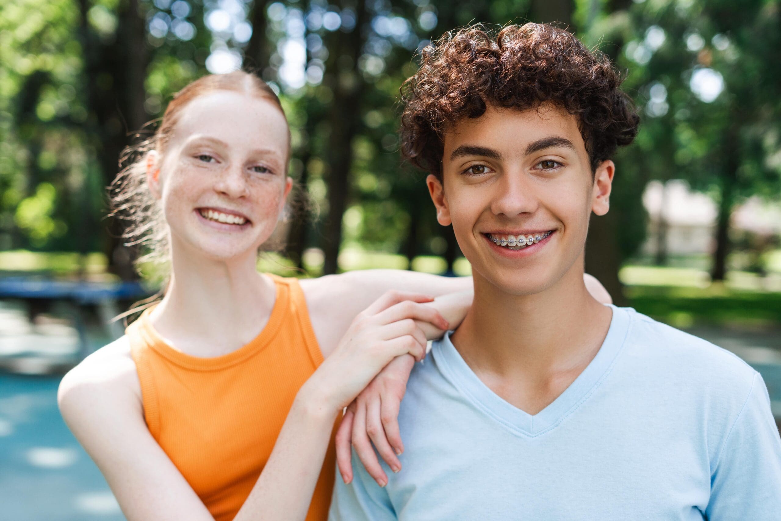 teenage friends embracing , one wearing braces